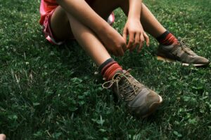person sitting on grass holding ankle after sprain - ankle sprain treatment Sydney