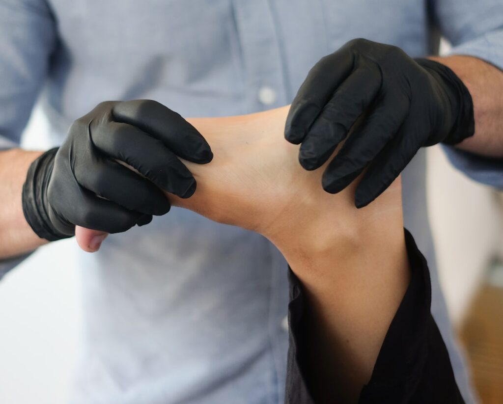 Podiatrist in clinical gloves examining patient heel for plantar fasciitis treatment in Sydney