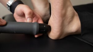Podiatrist applying shockwave therapy device to patient heel for plantar fasciitis treatment in Sydney